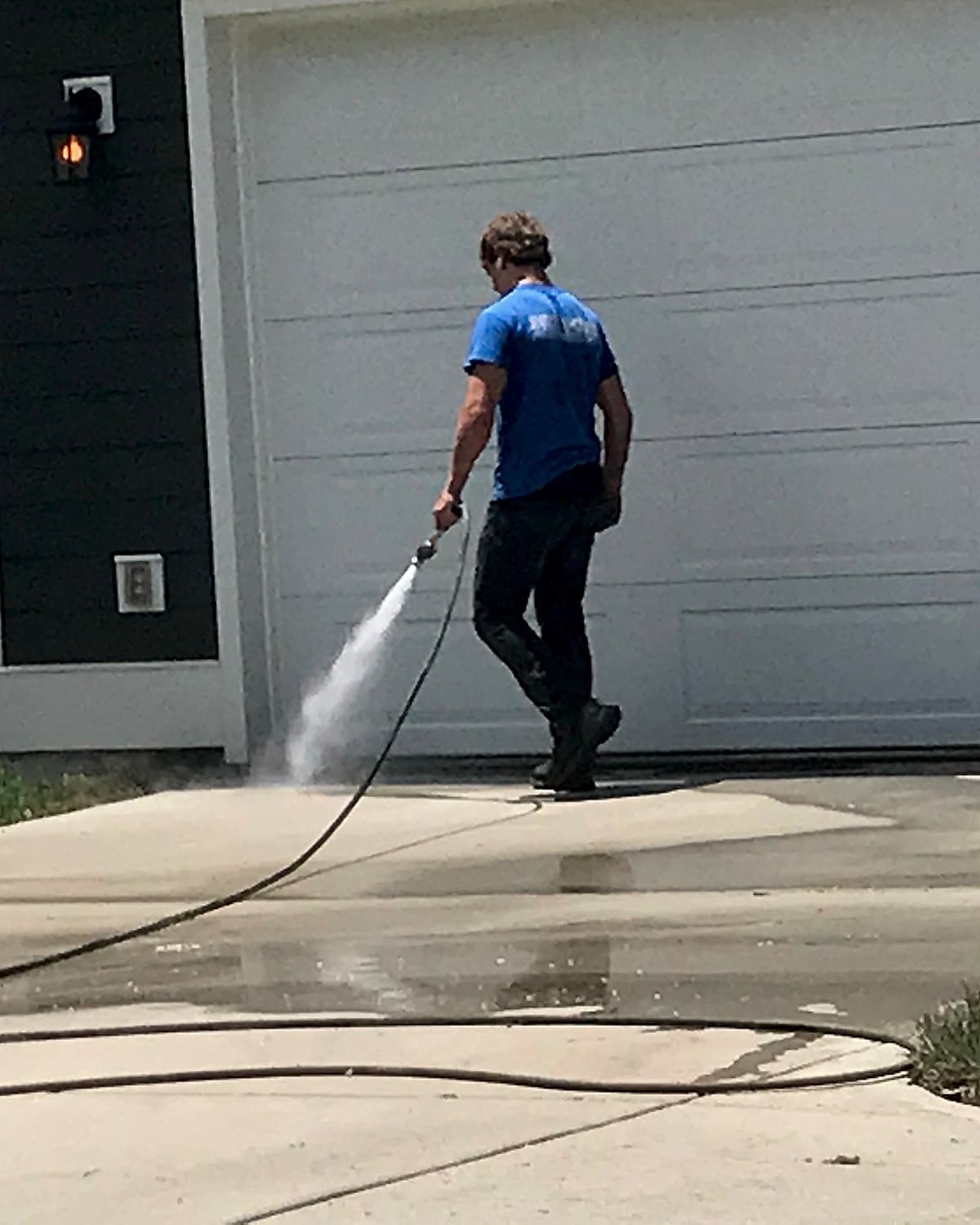 Jon Cross pressure washing a driveway in front of a garage